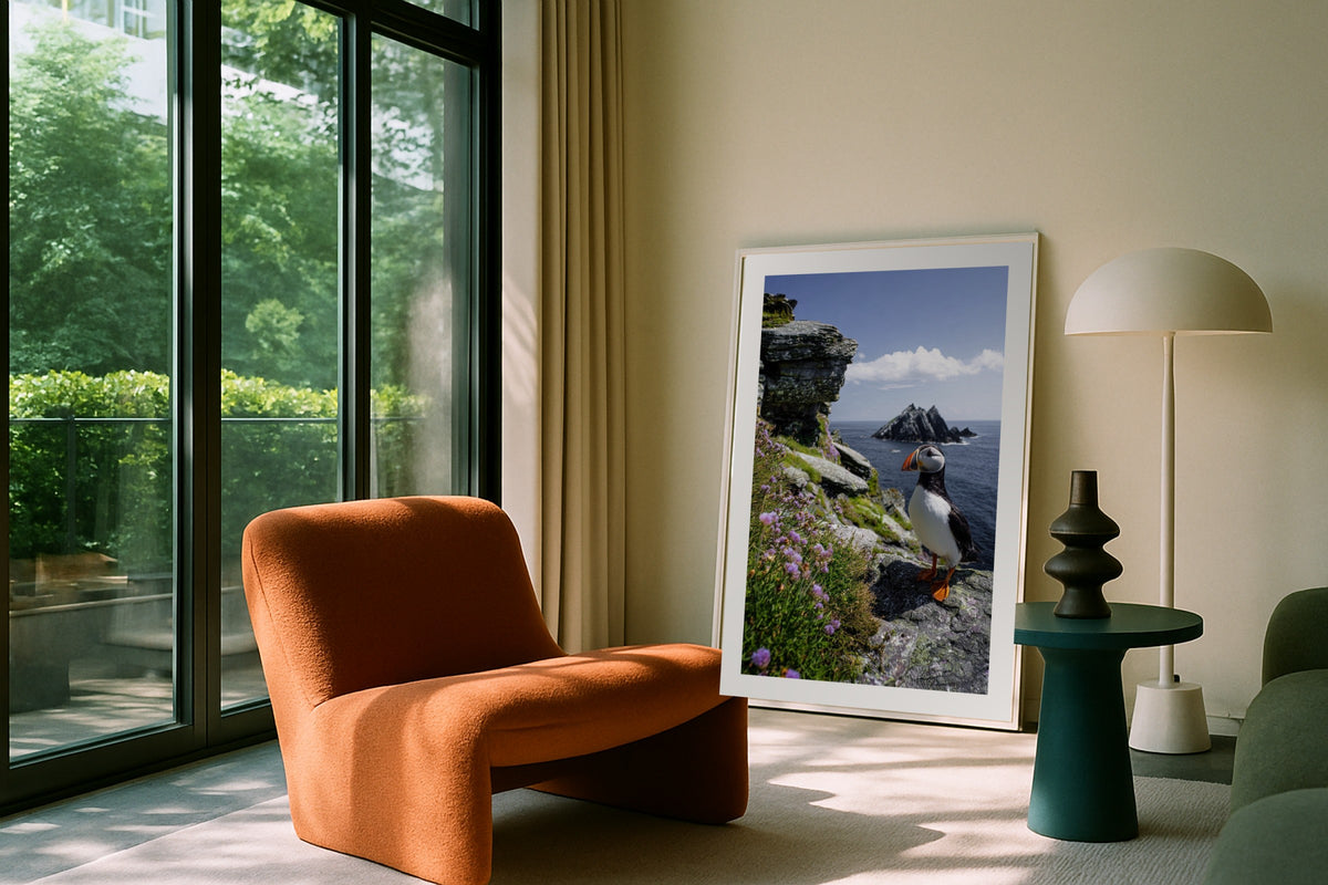 Cliffside Puffin wall art print, framed with a white border, in a leaning garden balcony