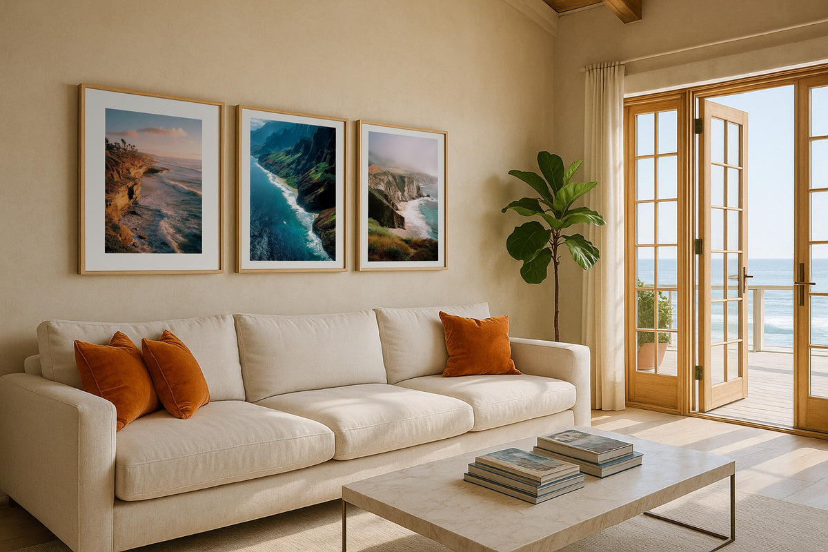 Gallery wall set of three coastal prints above a sofa: San Diego Cliffs, Na Pali Cliffs and Bixby Bridge