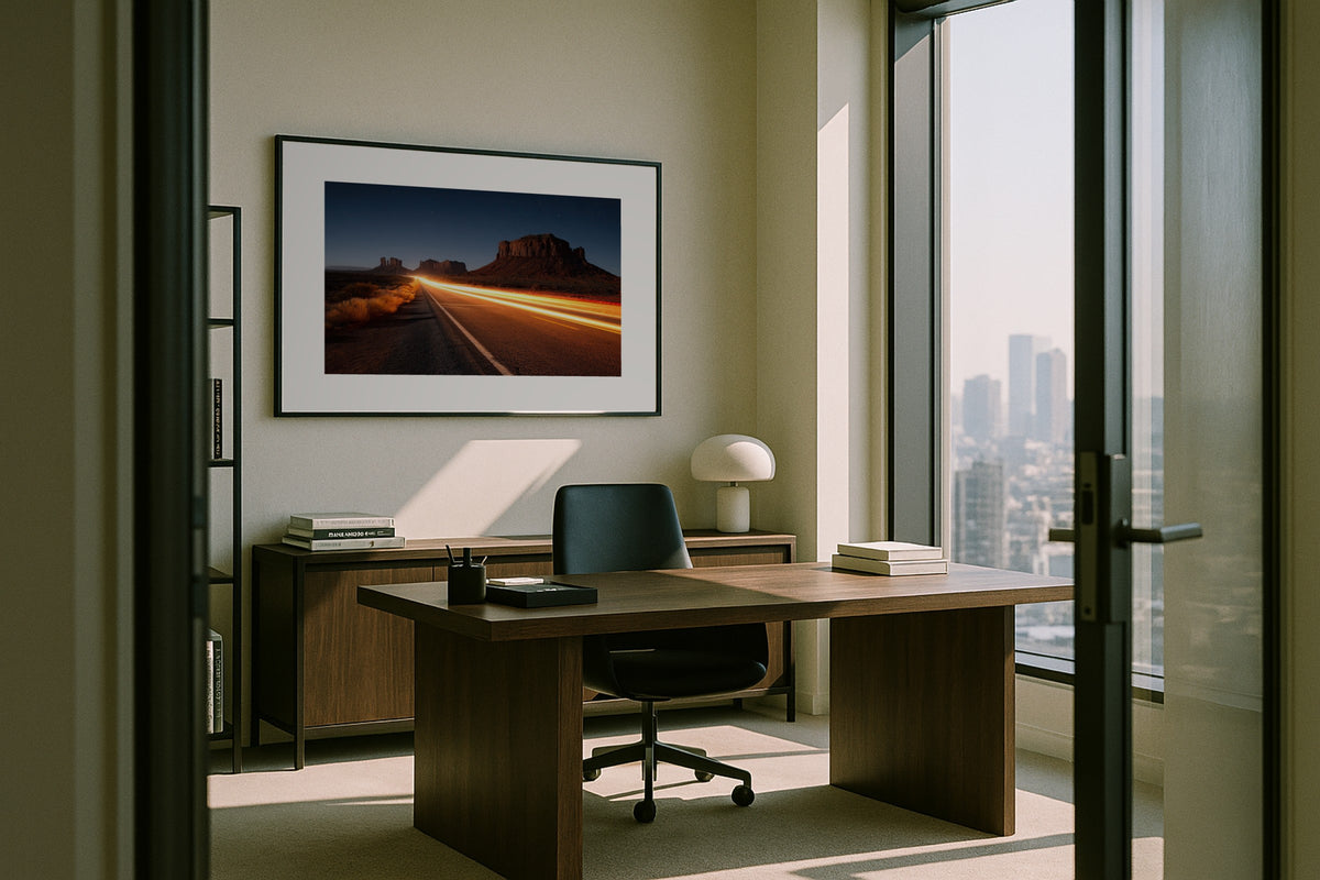 Monument Valley at Night wall art print, framed with a white border, in a city view executive desk