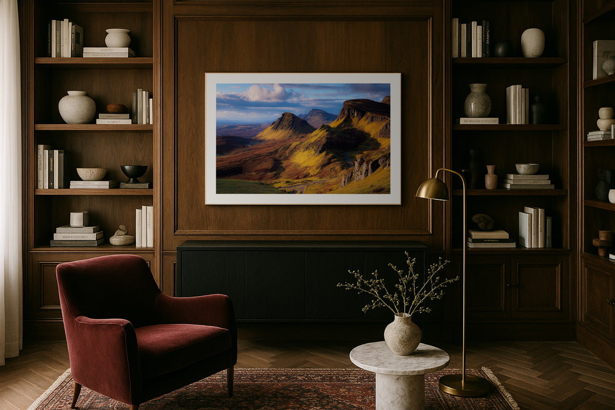 Quiraing Mountain Pass wall art print, framed with a white border, in a library wood panels velvet chair