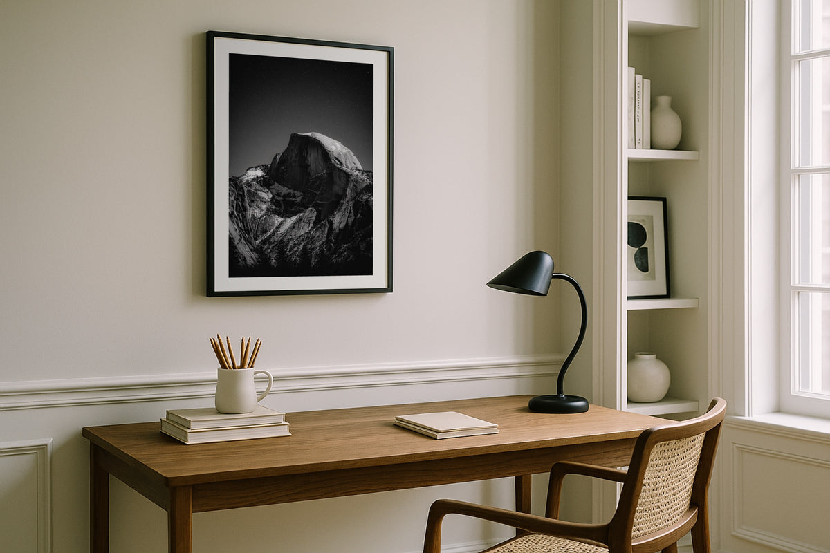 Half Dome at Night wall art print, framed with a white border, in a white desk black lamp